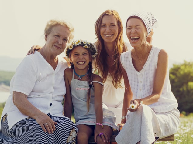 Four generations of female family members sitting together and laughing