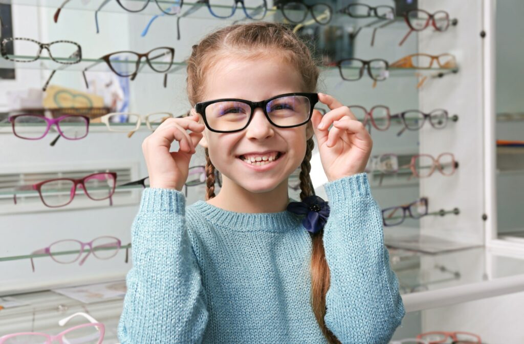 A young girl tries on new glasses at the optometrist's office to treat myopia progression
