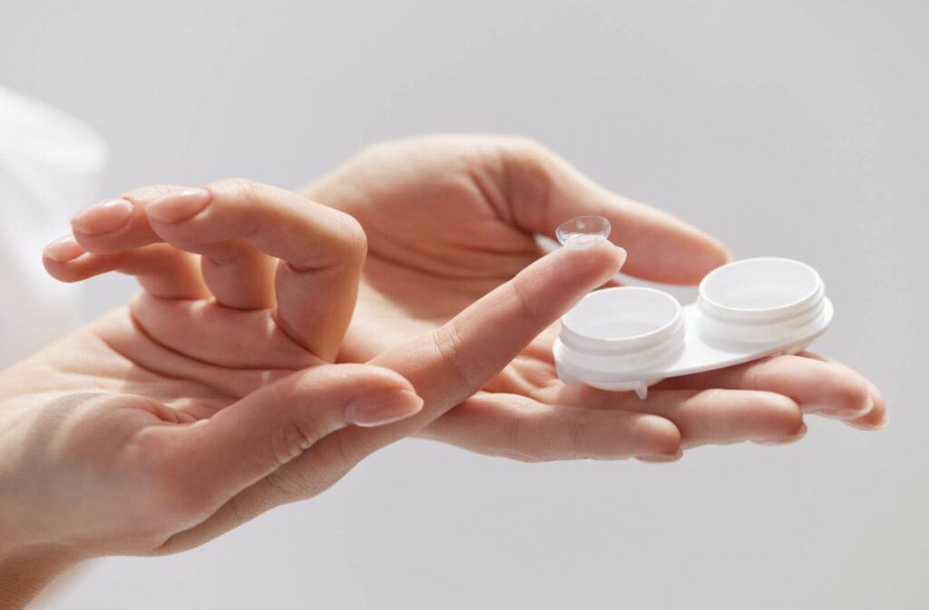 A woman holding out a contact lens case in her right hand and a contact lens on her left index finger