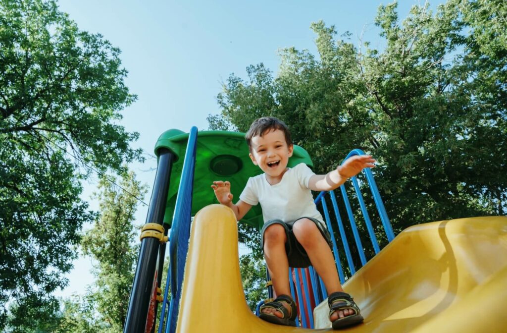 A young child happily plays on a slide without needing to wear corrective eyeglasses.