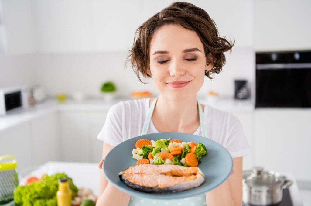 A person holds up an eye-healthy plate of salmon and veggies.