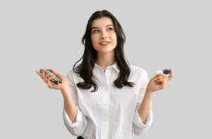 An optometry patient holding eyeglasses and contact lenses, trying to decide which to choose.
