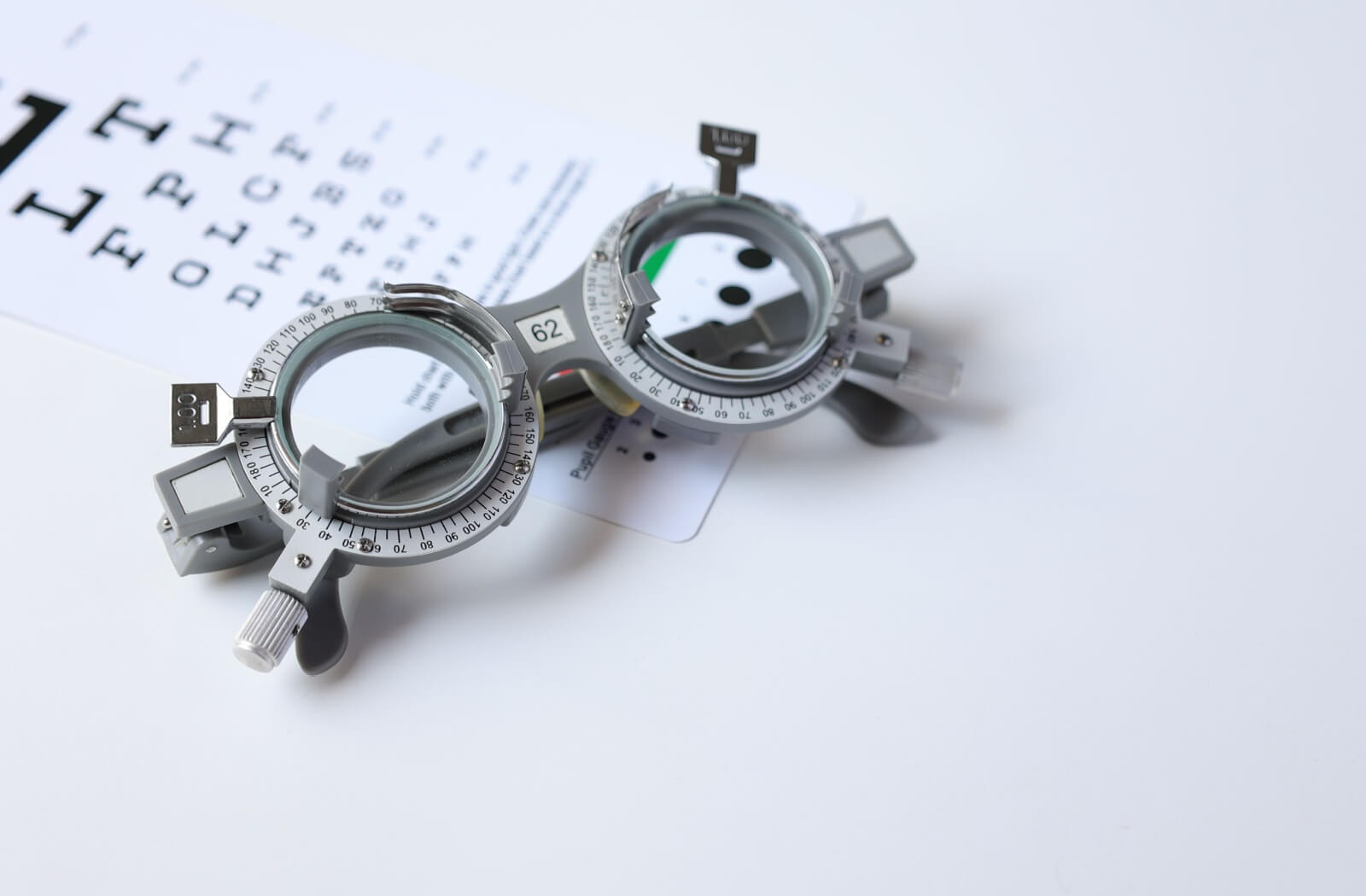 Optometry trial lens frame placed on top of an eye chart for vision testing.