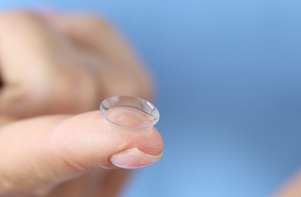 A close-up of a soft contact lens resting on a fingertip, showing the thin, transparent lens used for vision correction and contact lens wear.