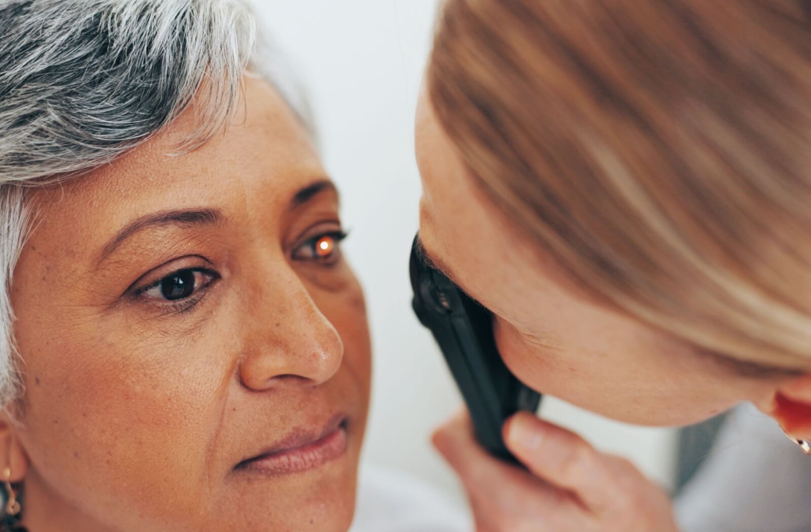 An optometrist performing a professional eye exam using a tonometer to check eye pressure for early signs of glaucoma in an older patient.